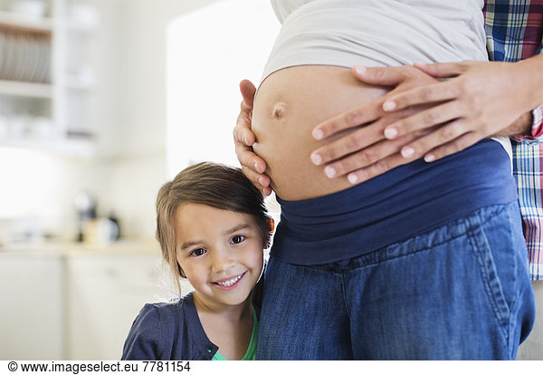 Girl smiling with pregnant mother’s belly