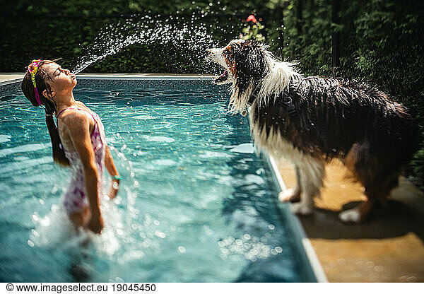 girl splashing her dog at the pool on a hot summer day