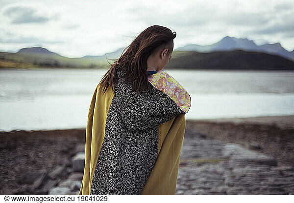girl stand in cloak by lake and mountains