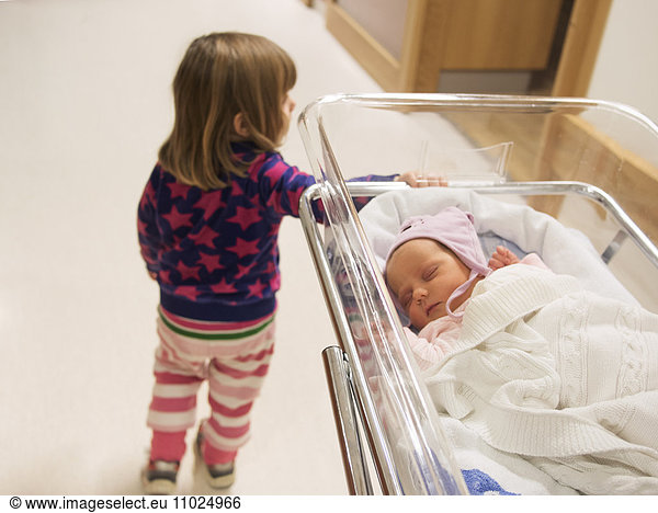 Girl standing by crib at hospital
