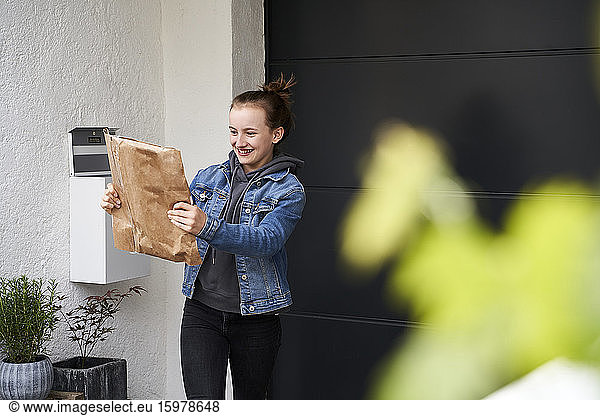 Girl standing in front of house  happy to receive a parcel
