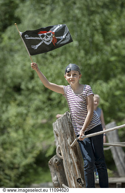 Girl standing on pirate ship and showing pirate flag in adventure playground  Bavaria  Germany