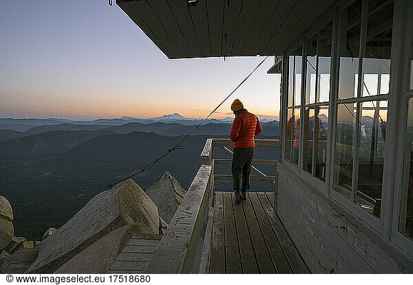 Girl standing on the deck of a fire lookout at sunset