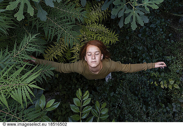 Girl standing with arms outstretched amidst plants