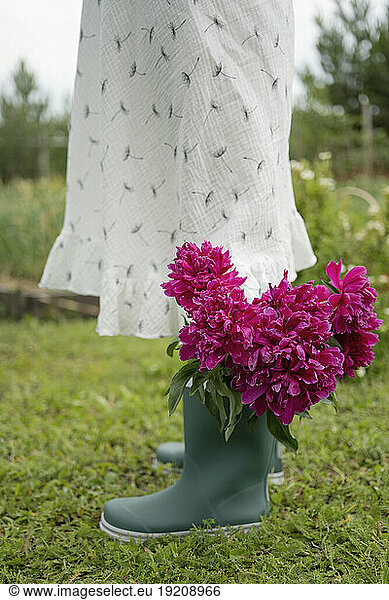Girl standing with flowers in rubber boot