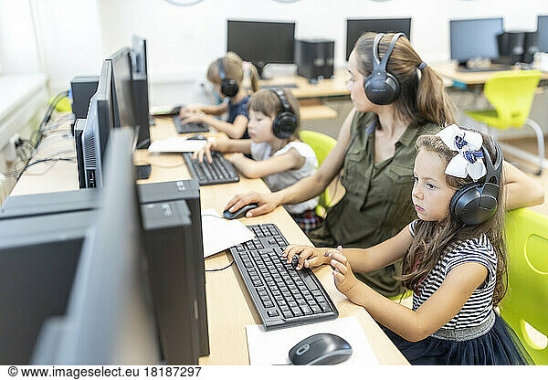 Girl studying through E-learning with teacher in class at school