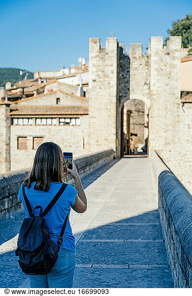 girl taking a picture on the medieval bridge of Besalú