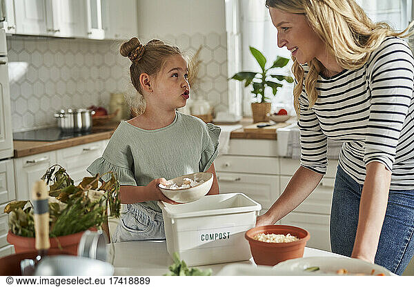 Girl talking with mother while making compost at home