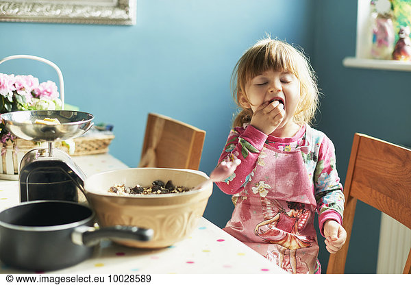Girl tasting baking ingredients in kitchen