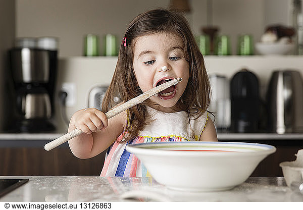 Girl tasting food on kitchen island at home