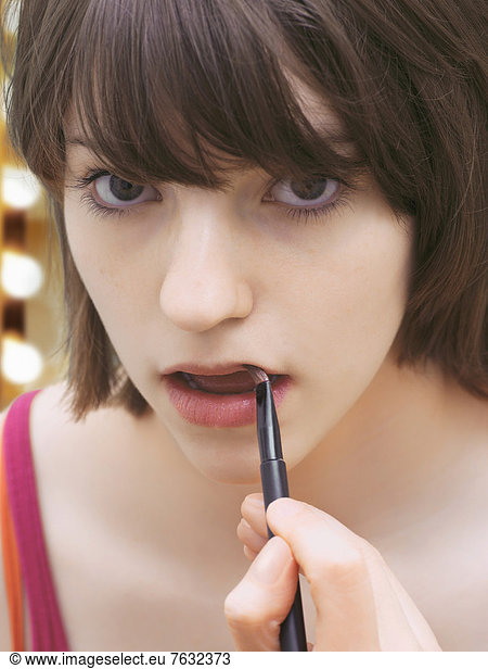 Girl  teenager  wearing make-up  applying lip gloss