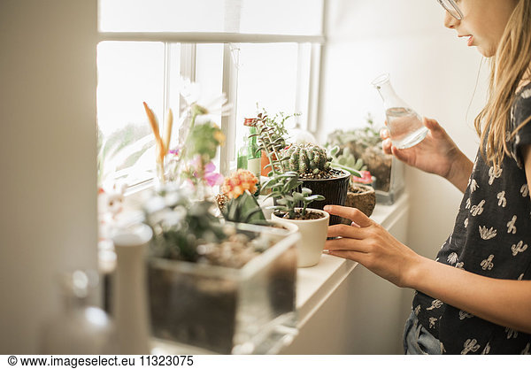 Girl tending plants on a sunny windowsill.