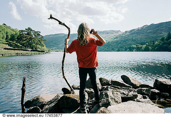 girl throwing stones and sticks into the water in Wales  UK