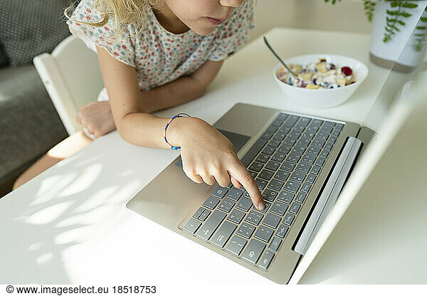 Girl typing on laptop keyboard at home