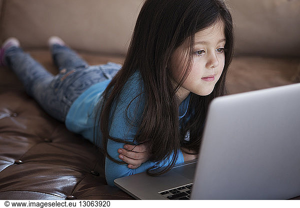 Girl using laptop computer while lying at home