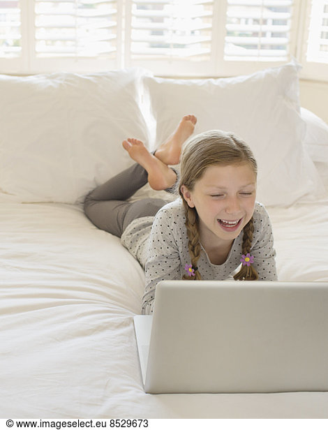 Girl using laptop on bed