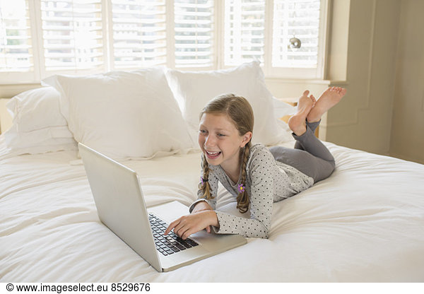 Girl using laptop on bed