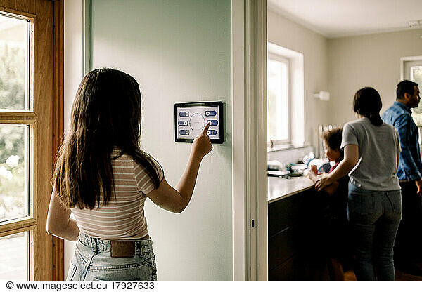 Girl using smart home app on digital tablet while standing near doorway