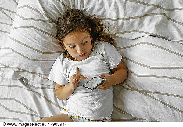 Girl using smart phone on bed at home