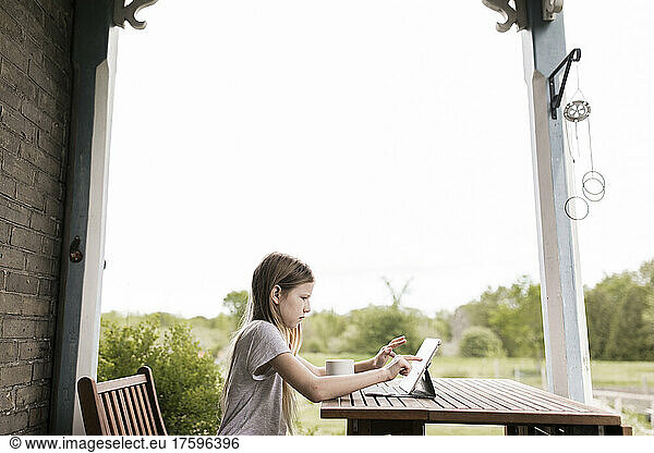 Girl using tablet computer on table at terrace