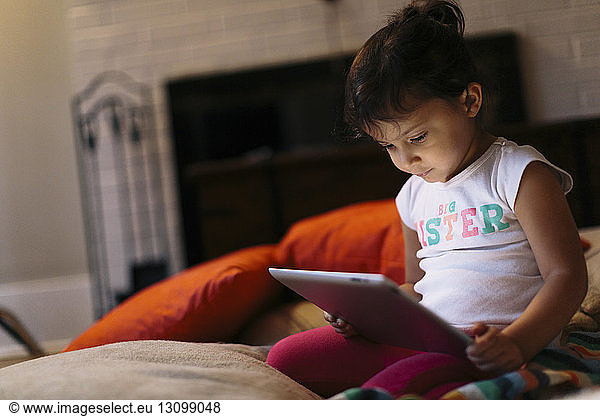 Girl using tablet computer while kneeling at home