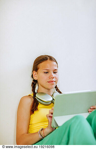 Girl using tablet PC in front of wall