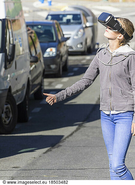 Girl using virtual reality headset while hitchhiking on road