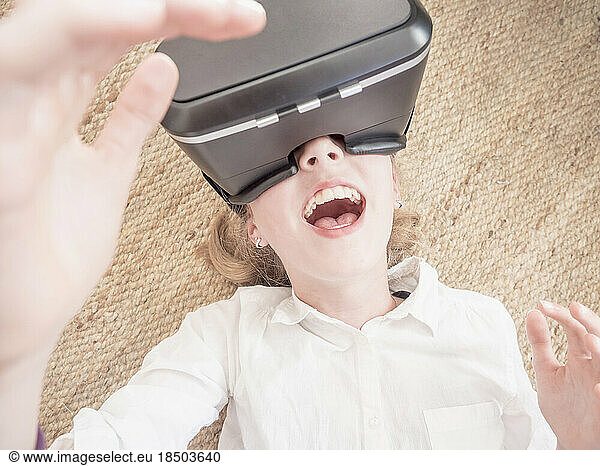 Girl using virtual reality headset while lying on floor