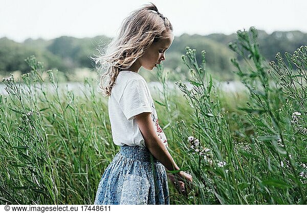 girl walking through flowers thoughtfully in summer