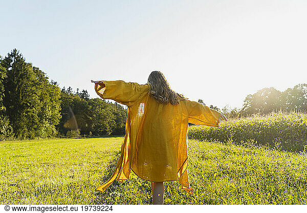 Girl walking with arms outstretched on grass