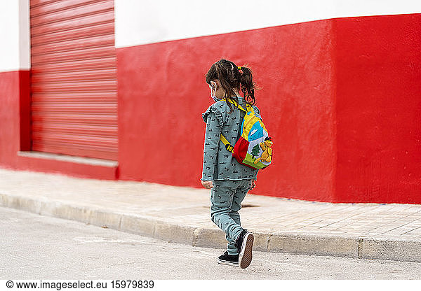Girl walking with backpack and mask on street