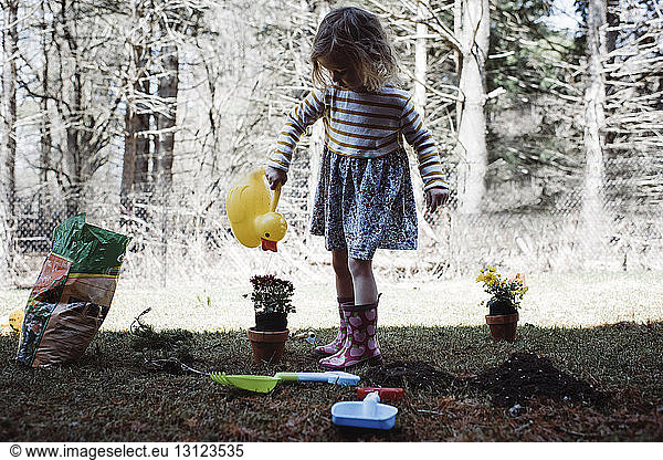 Girl watering potted plant in yard