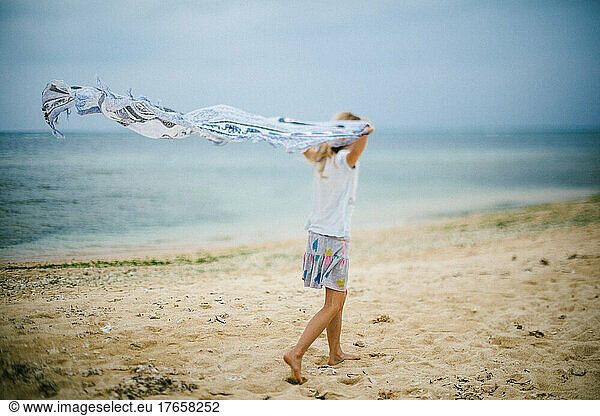Girl waves scarf along the beach shore