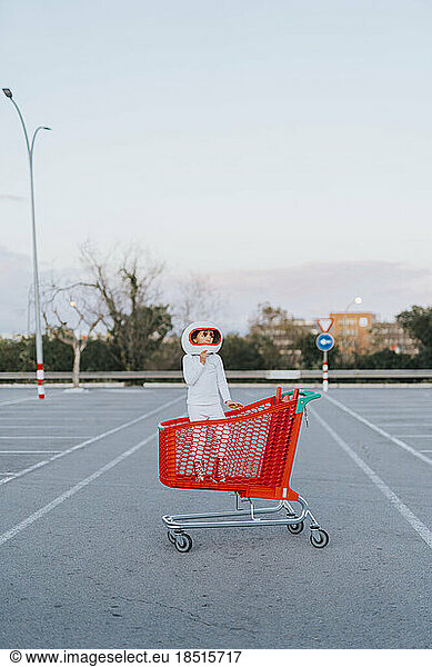 Girl wearing astronaut costume standing inside shopping cart