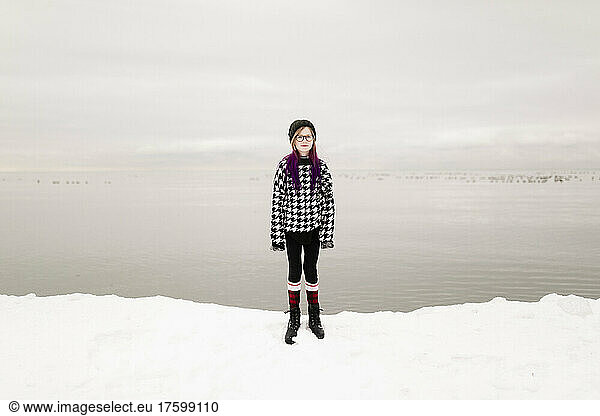 Girl wearing eyeglasses standing by lake in winter