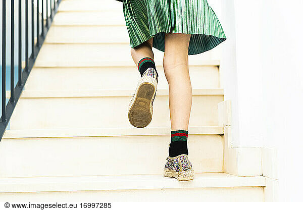 Girl wearing green skirt running upstairs