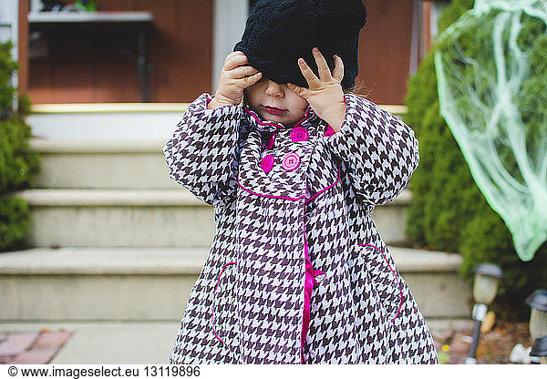 Girl wearing knit hat while standing in front yard