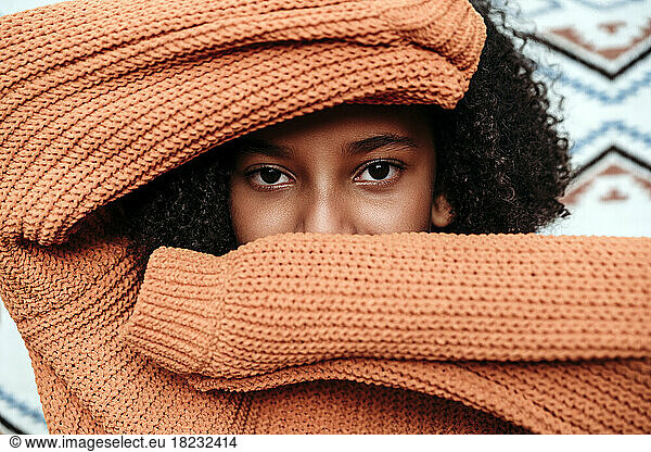 Girl wearing orange sweater covering face
