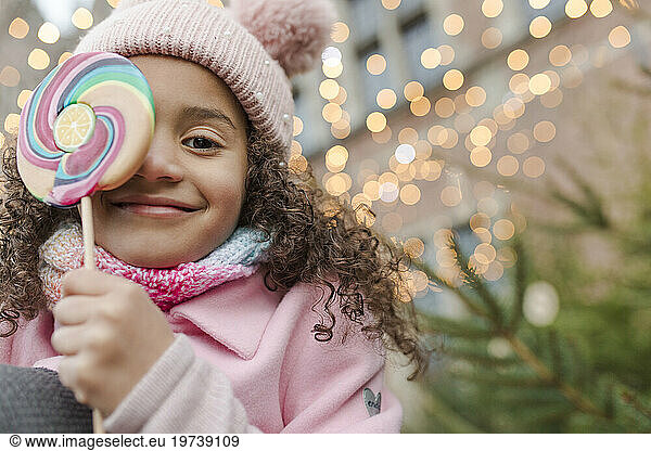 Girl wearing pink knit hat holding lollipop candy