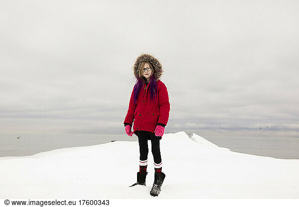Girl wearing red hooded jacket standing on snow in winter