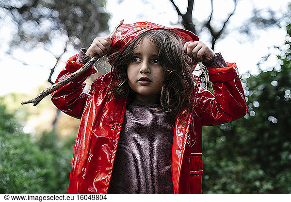 Girl wearing red rain jacket and hood in the woods