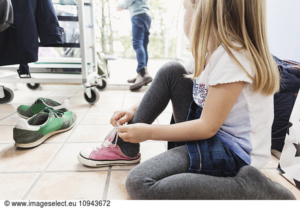 Girl wearing shoe while sitting on floor at day care center