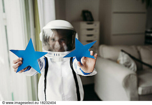 Girl wearing space costume showing blue stars at home