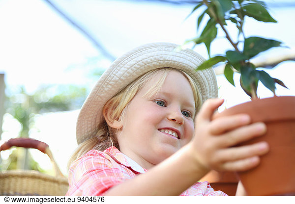 Girl wearing straw hat holding potted plant