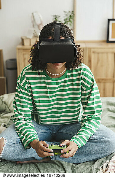 Girl wearing virtual reality simulators playing video game with controller at home