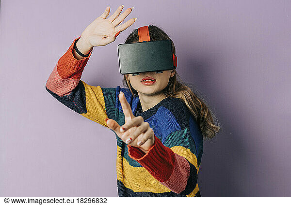 Girl wearing VR simulator gesturing against purple background