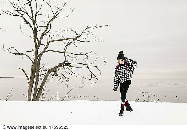 Girl wearing warm clothing walking on snow in winter