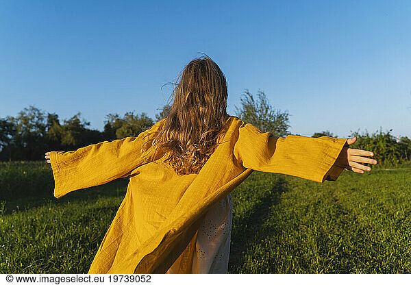 Girl with arms outstretched running in field