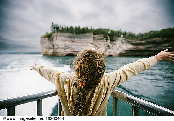 Girl with braids on boat at cliff on lake with wind in hair