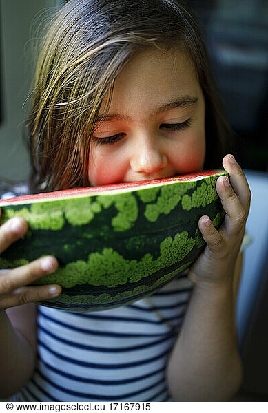 Girl with brown hair eating fresh watermelon